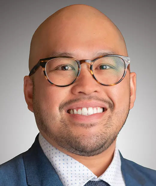 A man with glasses and bald head smiling.