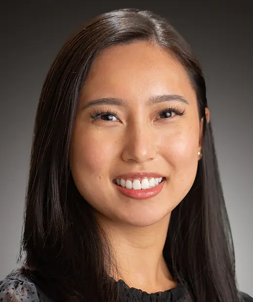 A woman with long black hair smiles for the camera.