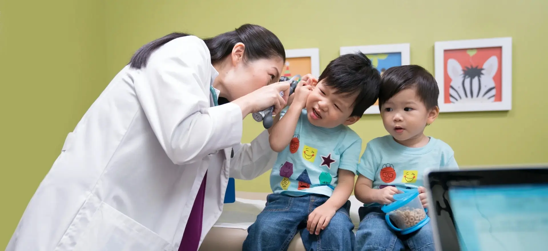 A doctor examines two children 's eyes.