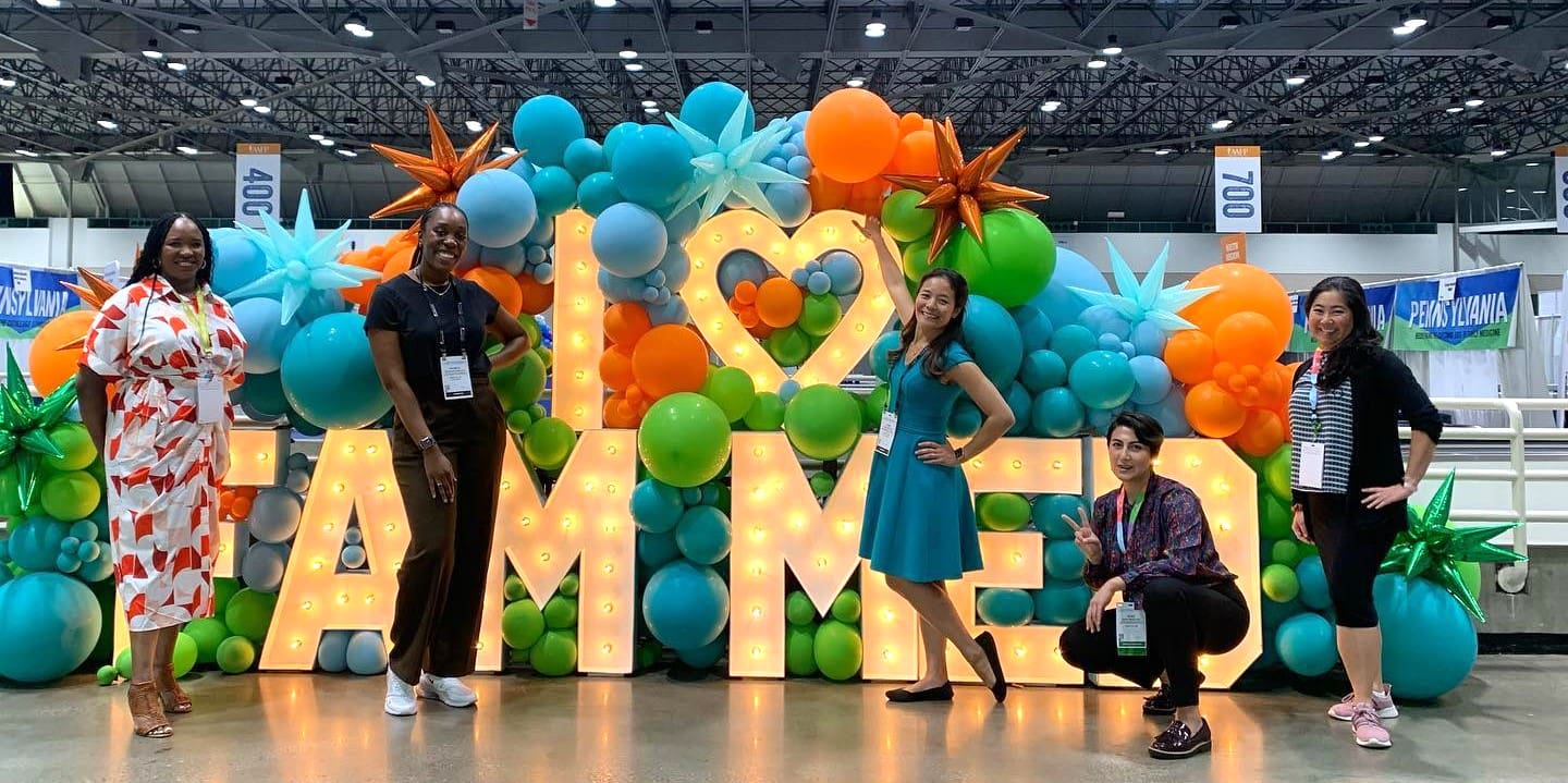 A group of people standing in front of balloons.