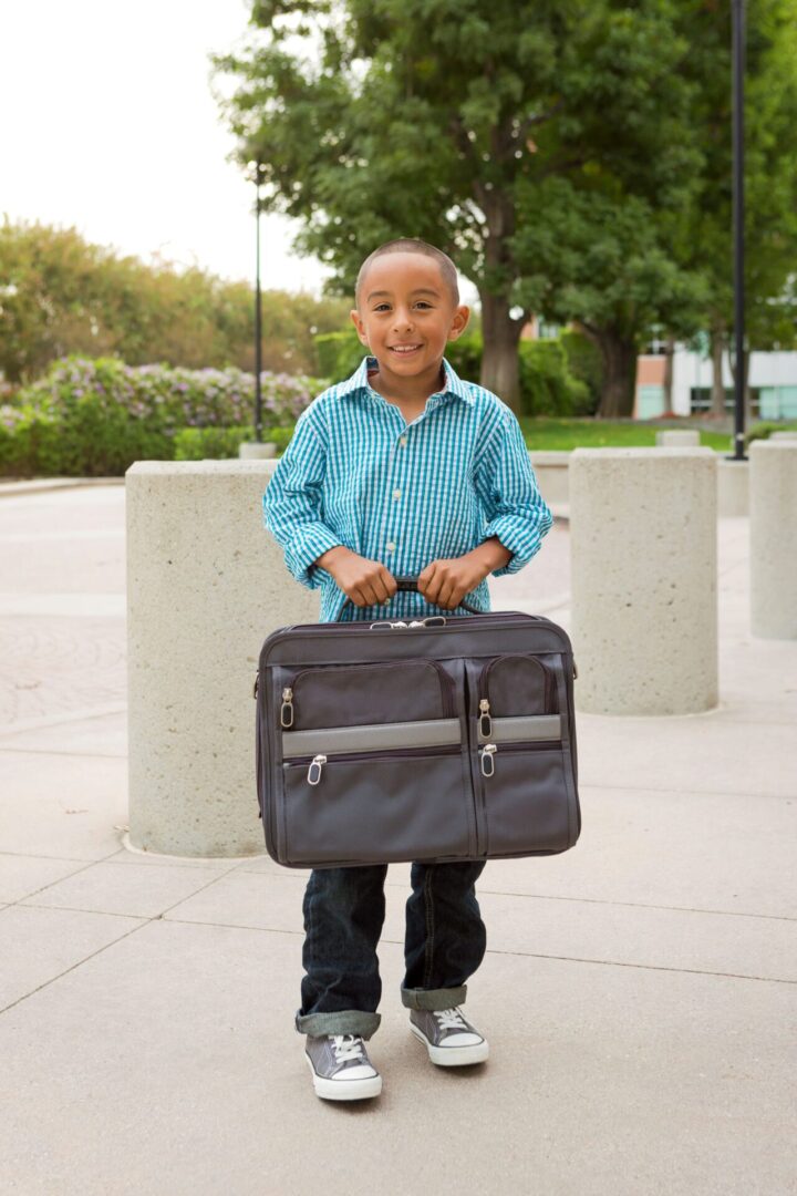 A young boy holding onto a black bag