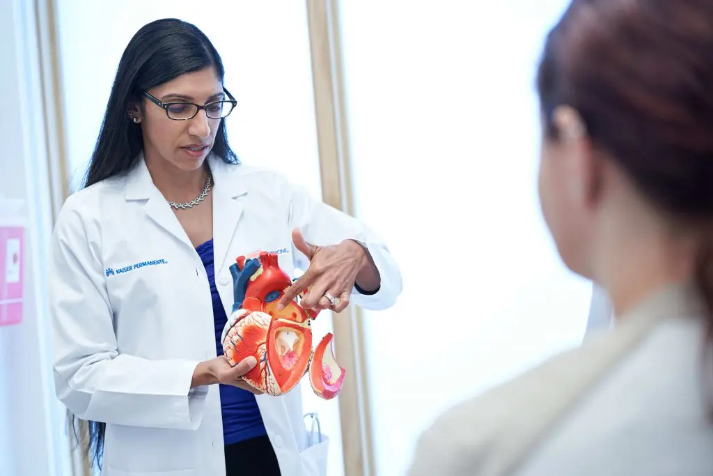 A woman in white lab coat holding up a model of an animal.