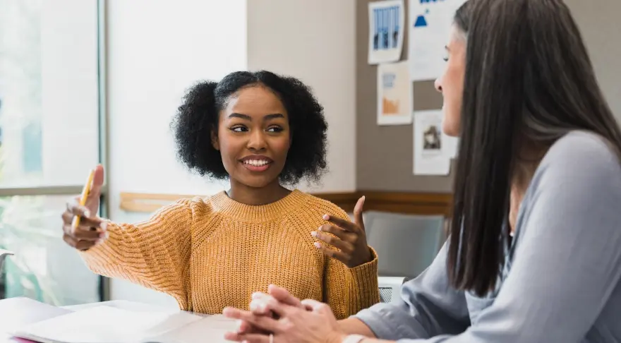 Two women are sitting at a table talking.