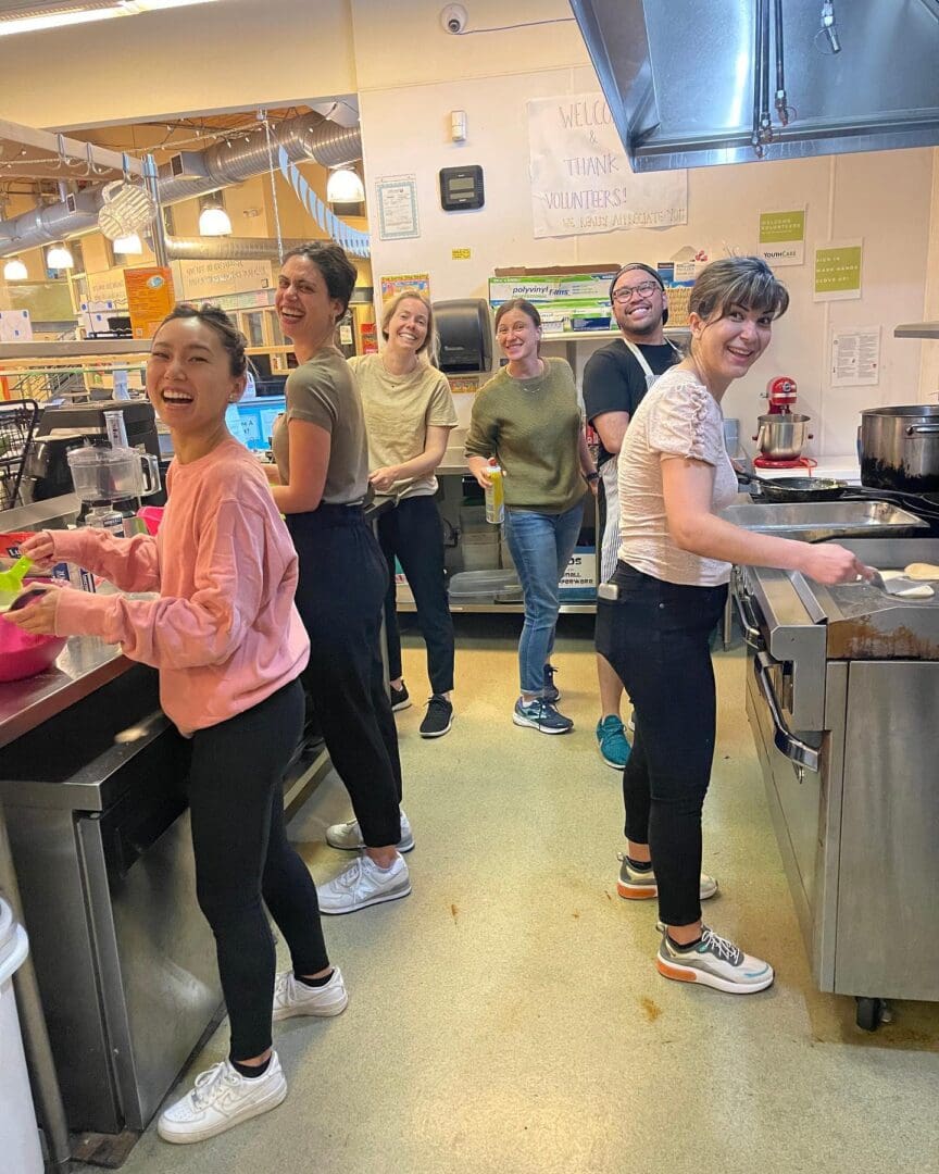 A group of people standing in a kitchen preparing food.