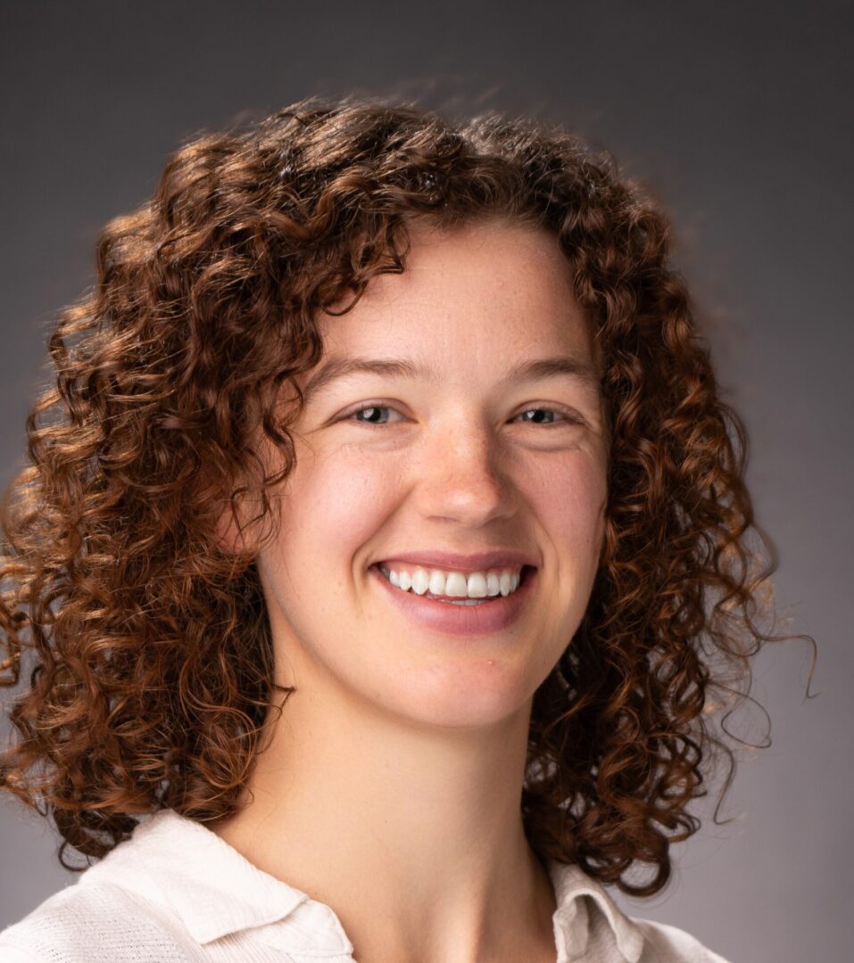 A woman with curly hair smiling for the camera.