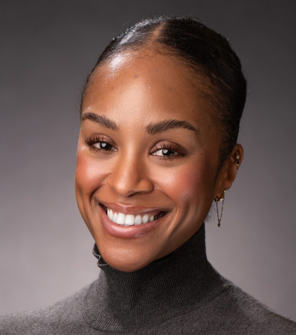 A woman with a black sweater smiles for the camera.